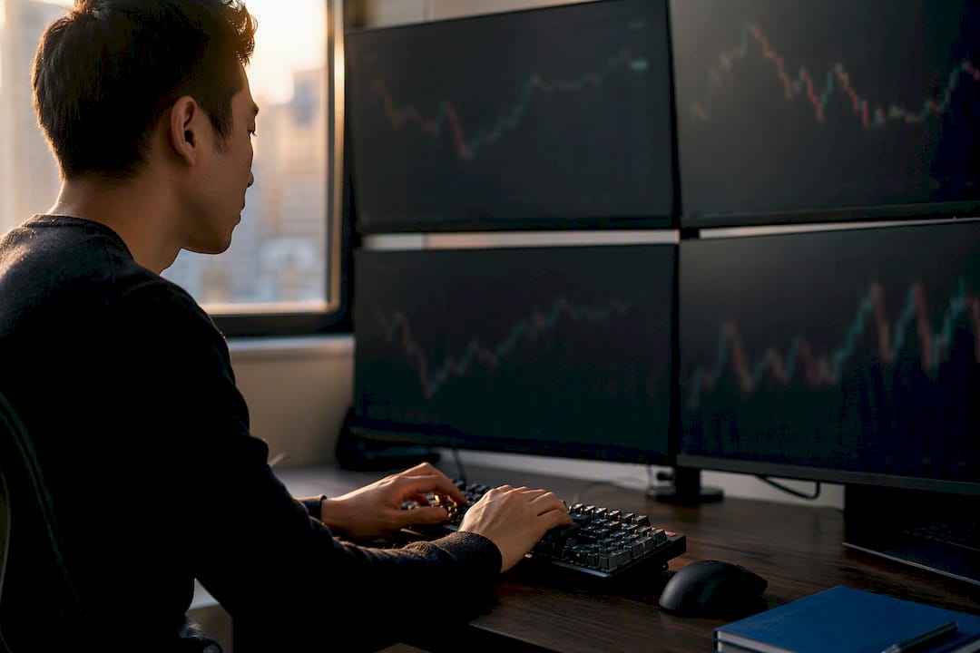 Trader hands adjusting dark monitors in modern workspace